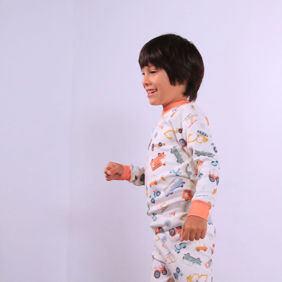 Child against white wall wearing Organic pajamas made in San Francisco with vintage cars and trucks prints. Detail of flatlog seam for sensitive skin. 100% cotton threads to avoid irritation.