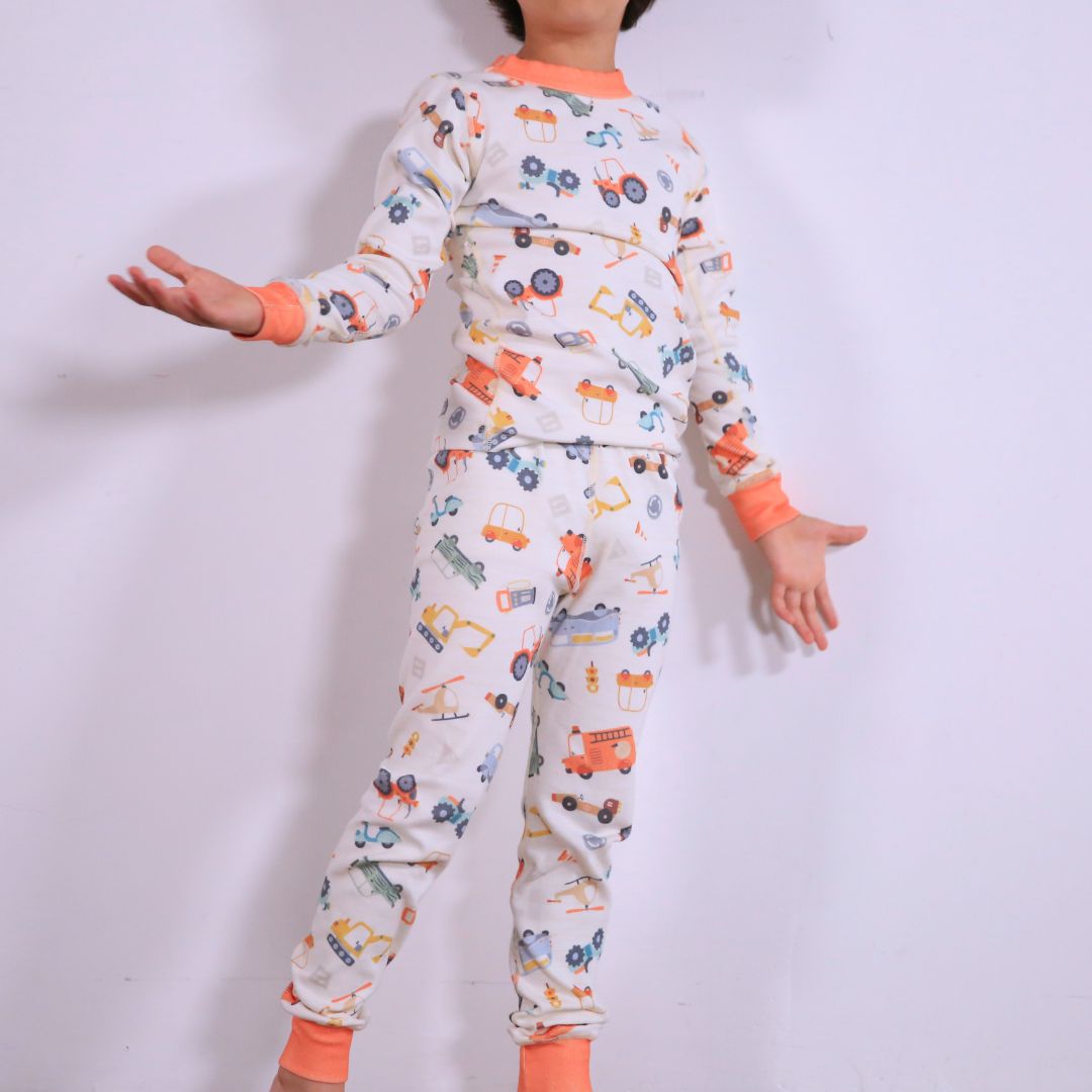 Child against white wall wearing Organic pajamas made in San Francisco with vintage cars and trucks prints. Detail of flatlog seam for sensitive skin. 100% cotton threads to avoid irritation.