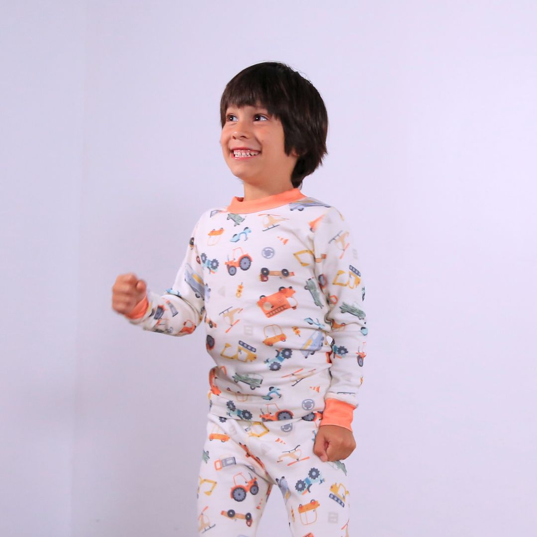 Child against white wall wearing Organic pajamas made in San Francisco with vintage cars and trucks prints. Detail of flatlog seam for sensitive skin. 100% cotton threads to avoid irritation.